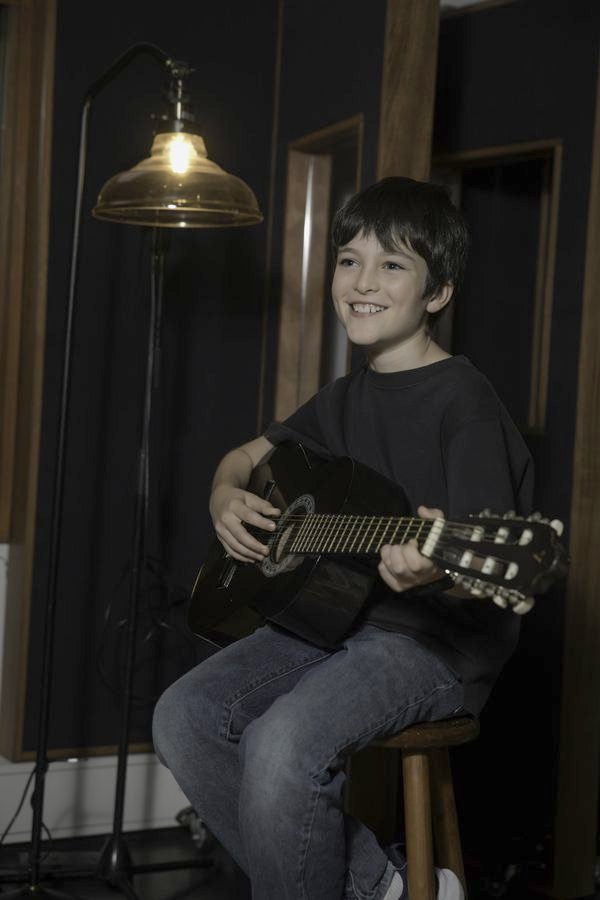 A young guitarist smiling during a lesson
